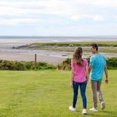 Couple holding hand walking toward a beach