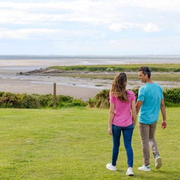 Couple holding hand walking toward a beach