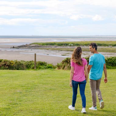 Couple holding hand walking toward a beach