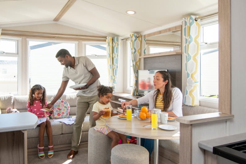 Family sat at table in caravan eating breakfast