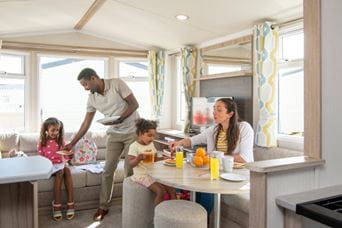 Family sat at table in caravan eating breakfast