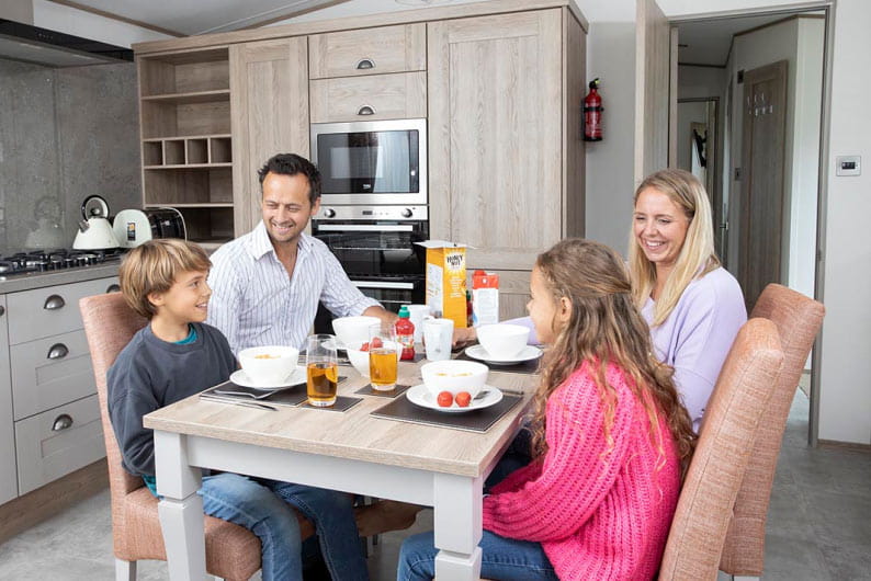Family sat around dining table eating and laughing