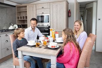 Family sat around dining table eating and laughing