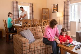 Muma and daughter reading whilst dad and daughter set the dining table
