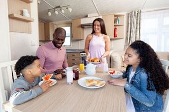 Family sat chatting around dining table in caravan