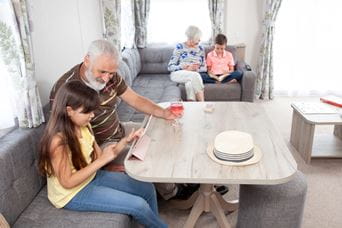 Grandad and granddaughter reading around the dining table