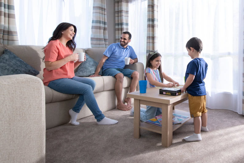 Family sat on sofa talking and playing games