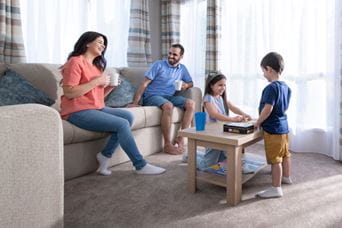 Family sat on sofa talking and playing games