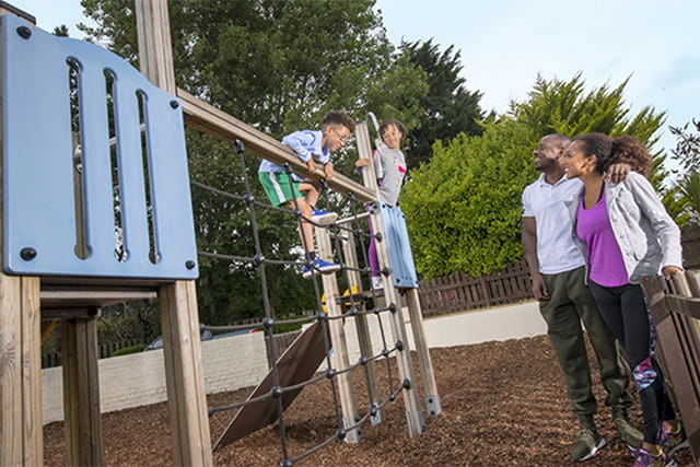 Kids playing on the adventure playground whilst parents watch