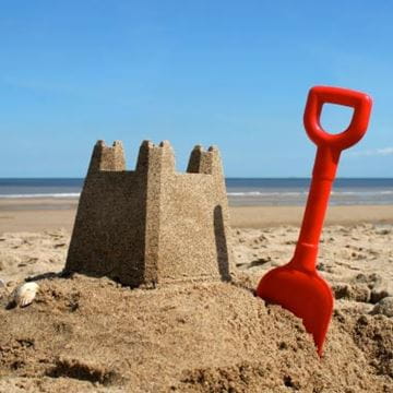 a sandcastle with a red spade next to it