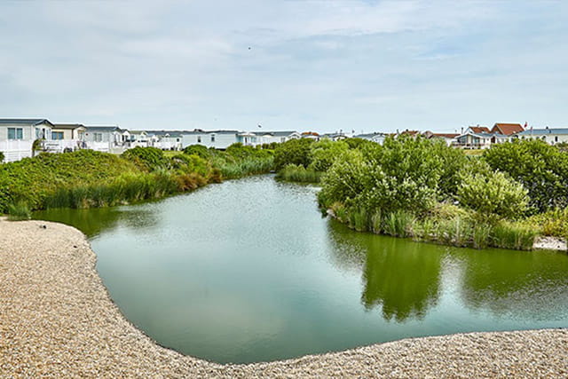 A view of caravans overlooking the fishing lake at Romney Sands Holiday Park