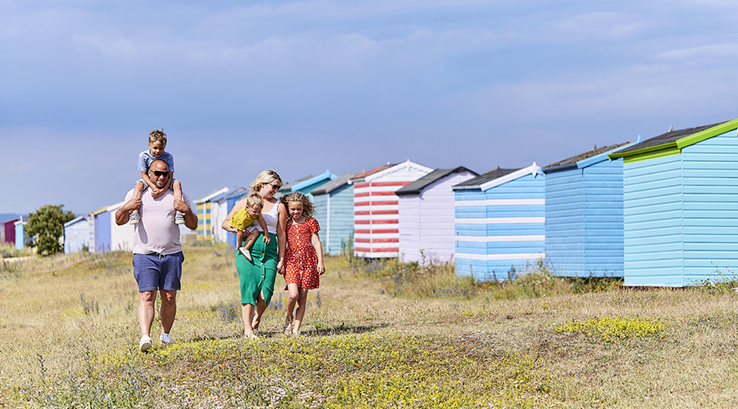 a family walking past beach huts