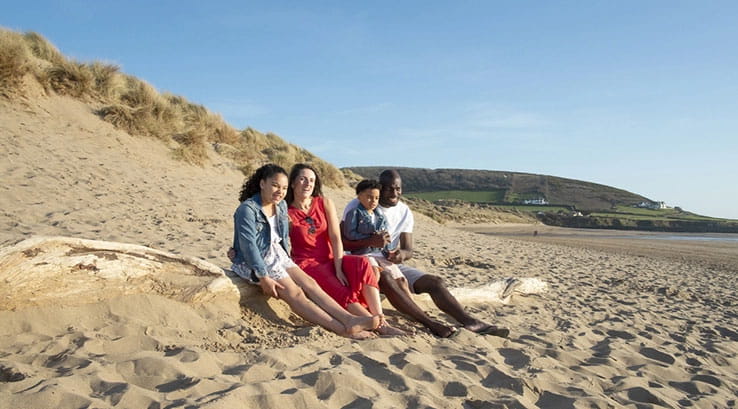 A family sitting on a sandy beach looking out to sea