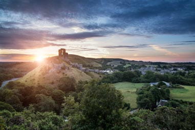 The sun setting behind Corfe Castle