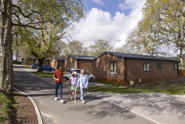 A family walking past holiday lodges at Sandford Holiday Park