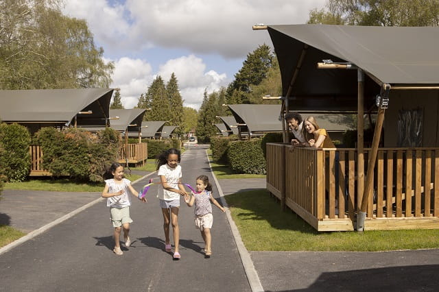 A family walking past glamping tent accommodation at Sandford Holiday Park