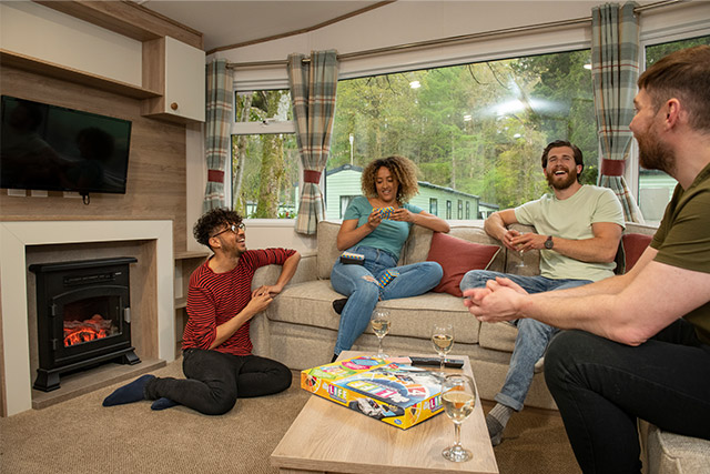 A group of friends socialising with a glass of wine in their holiday caravan at Sandylands Holiday Park