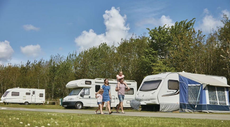 A family strolling through the touring and camping pitches on park