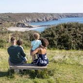 A family sitting on a bench looking out at the sea view