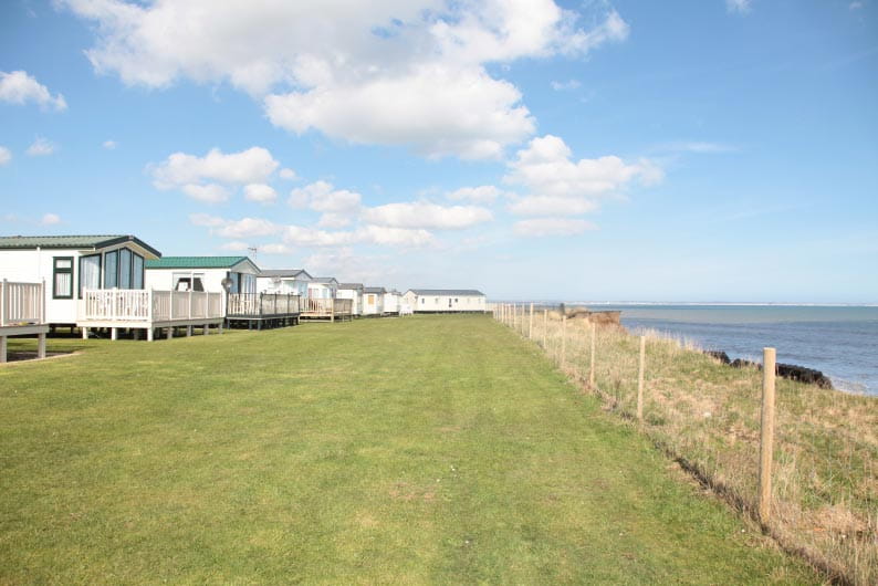 Holiday park caravans on grass lawn overlooking the beach