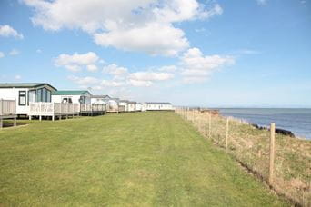 Holiday park caravans on grass lawn overlooking the beach