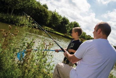 Father and son fishing in by the side of a lake