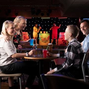 Family seating enjoying drinks with entertainment on a stage behind