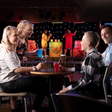Family seating enjoying drinks with entertainment on a stage behind