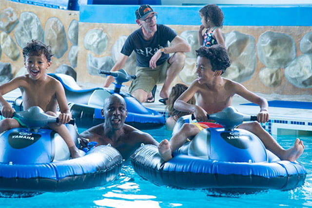 Kids riding inflatable jet skis in the indoor swimming pool at Southerness Holiday Park