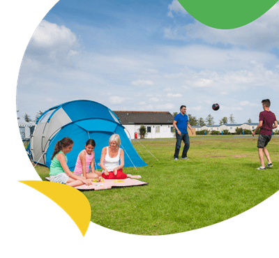 A family relaxing and playing football outside their tent at Southerness Holiday Park