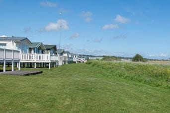 Row of white holiday park lodges in green space