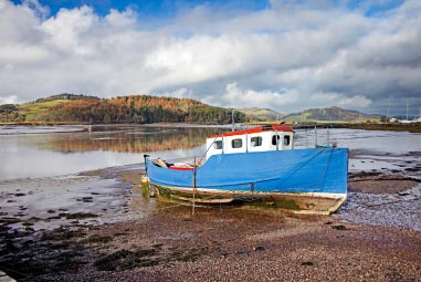 Boat docked on beach with hills in the distance
