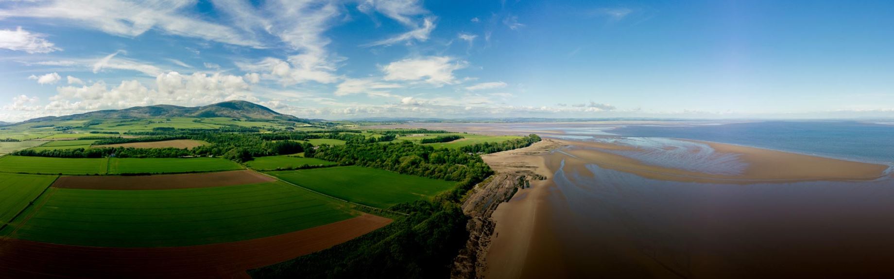 Sprawling views of fields, woodlands a sandy beach and sea