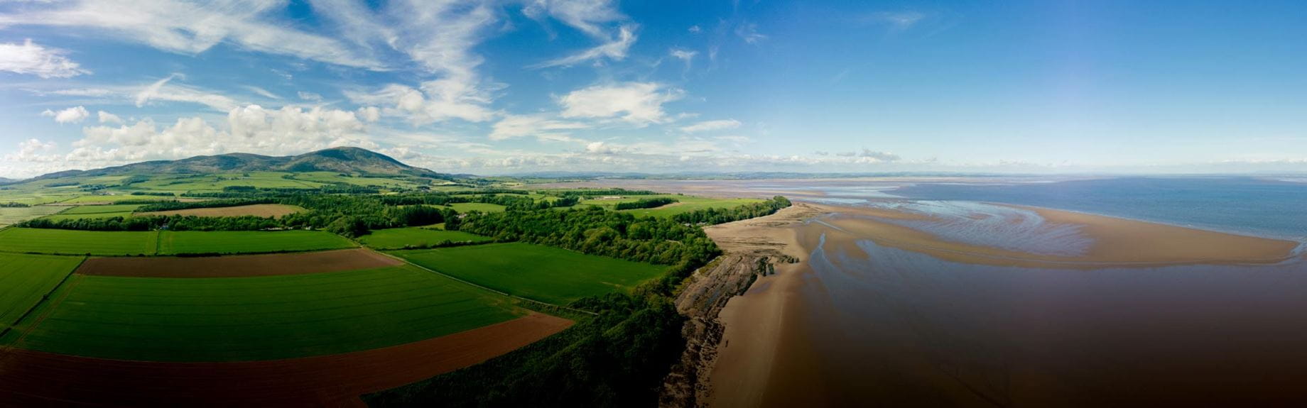Sprawling views of fields, woodlands a sandy beach and sea