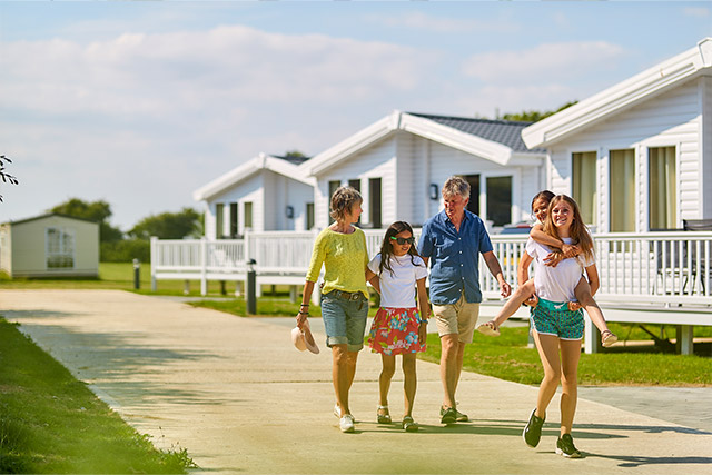 A family walking past holiday accommodation caravans at St Margaret's Bay Holiday Park