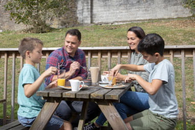 A family enjoying a meal outdoors at a picnic table
