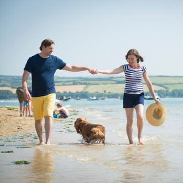 A couple walking on the beach with their dog