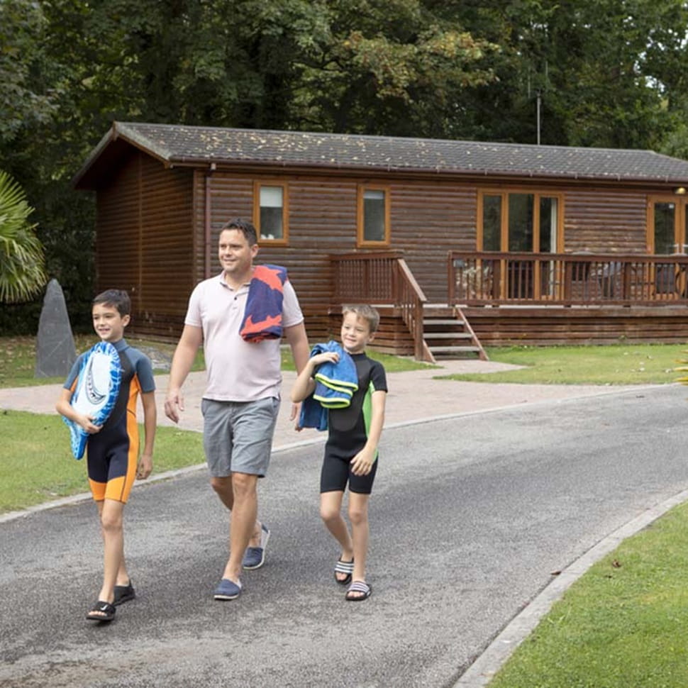 father and two sons walking past holiday lodges