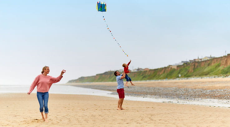 family flying a kite on the beach