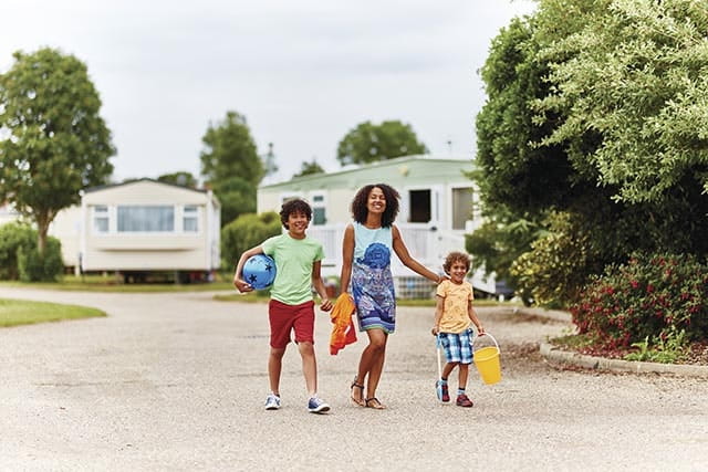 Mother and children walk in front of park homes at Summerfields Holiday Park