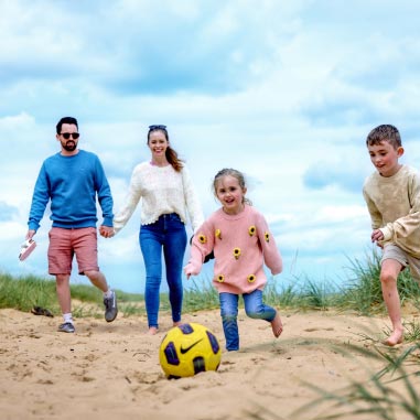 a family playing with a football on the beach