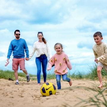 a family playing with a football on the beach