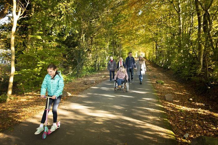 A family taking a walk  along an autumnal tree lined path at Sundrum Castle Holiday Park