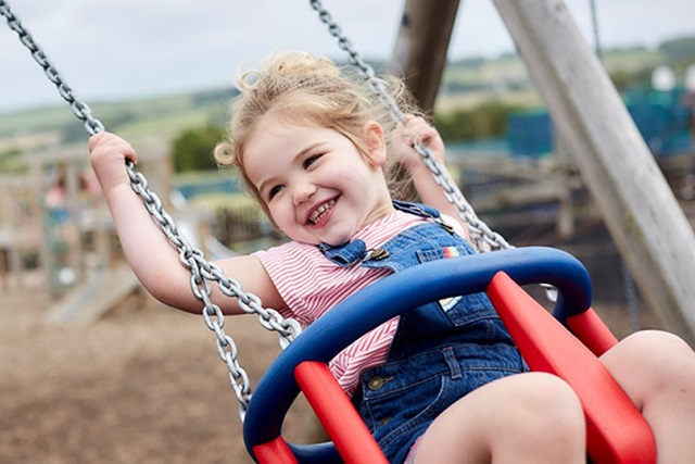 A little girl swinging on a swing on the playground at Thorness Bay