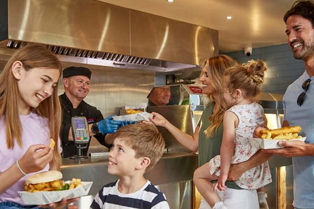 A family ordering fish and chips from the takeaway at Thorness Bay