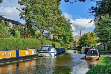 Colourful boats on a canal with houses peeping through the bankside
