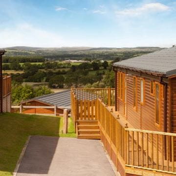 Wooden holiday home lodge and terrace with view of fields and trees