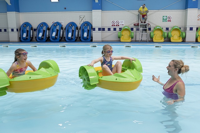 Mother and two children in Aqua Paddlers in the indoor pool at Torquay Holiday Park