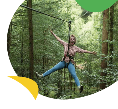 A lady on a rope in the trees at Go Ape near Trecco Bay Holiday Park