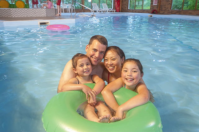 A family posing around a rubber ring in the indoor swimming pool